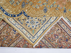 A vintage Persian Tabriz rug with intricate floral patterns in blue, gold, and red tones.