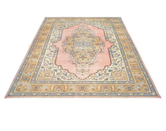 A vintage Persian Tabriz rug featuring an intricate floral medallion on a soft pink field.