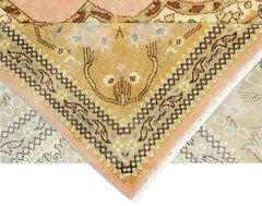A corner of a vintage Persian Tabriz rug showing intricate floral patterns in peach and gold.