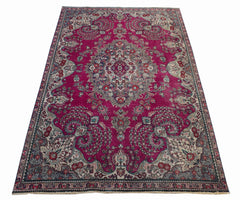 A vintage Persian Tabriz rug featuring an intricate floral medallion on a deep magenta field.