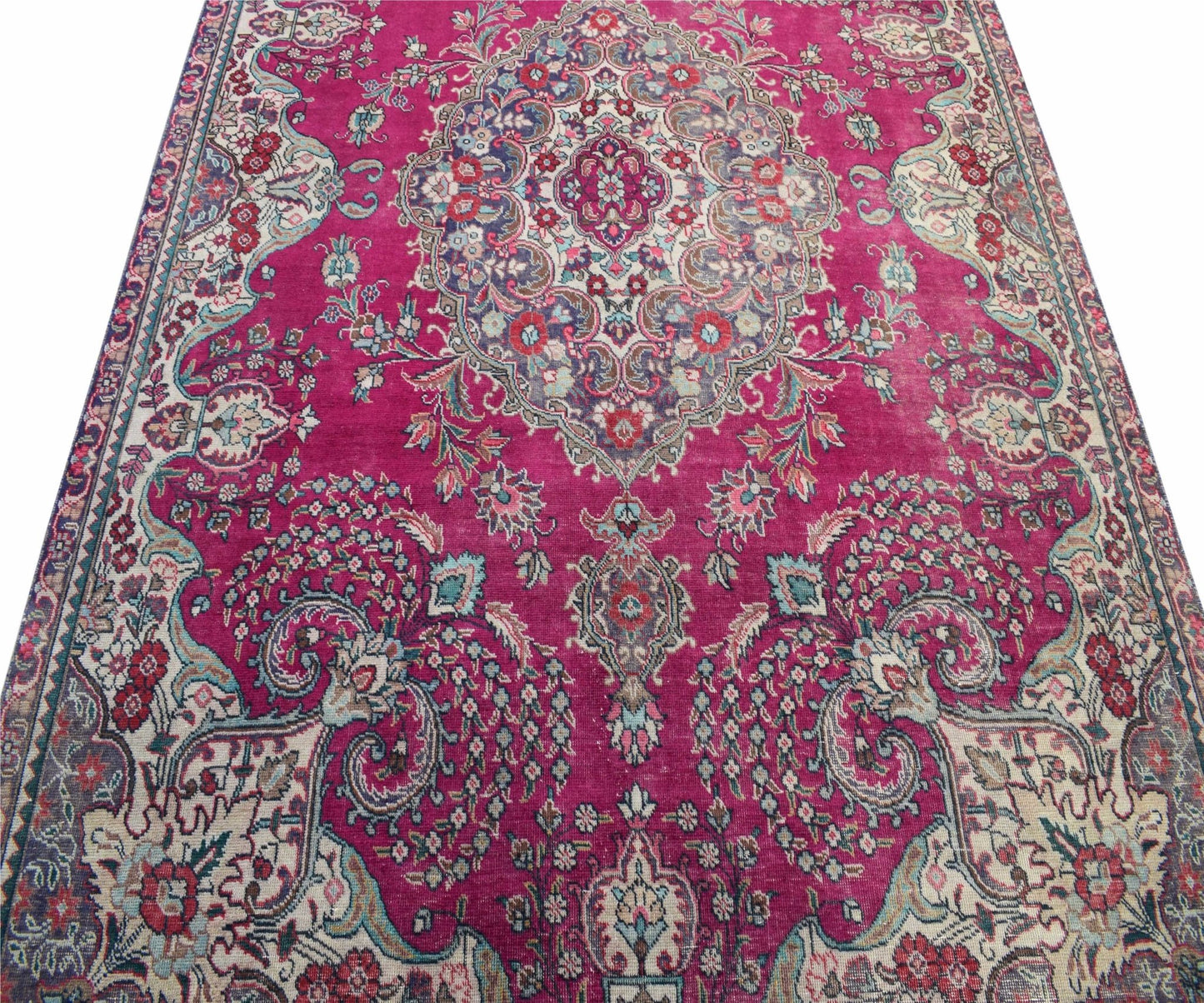 A vintage Persian Tabriz rug featuring a central medallion and intricate floral patterns in magenta.
