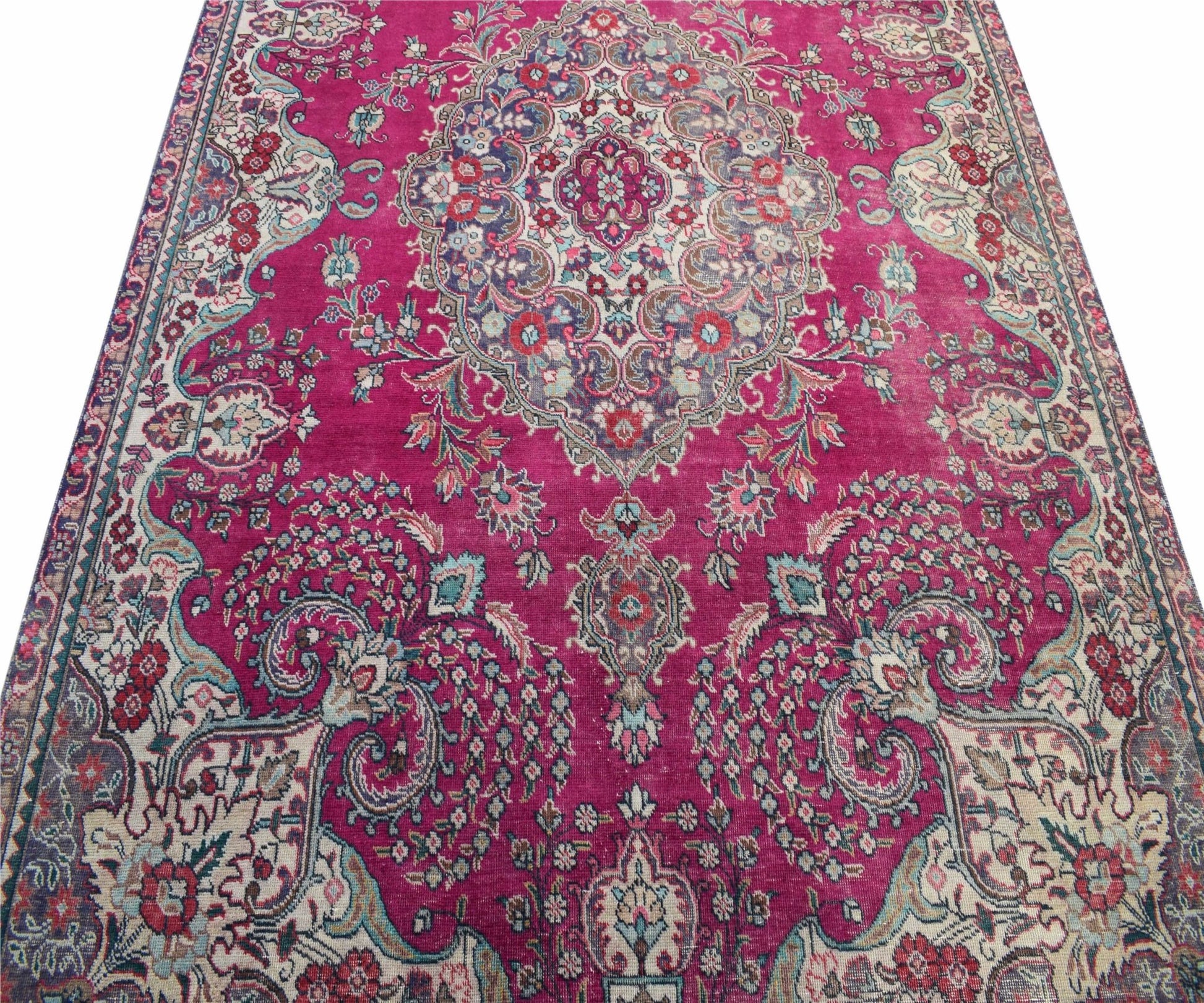 A vintage Persian Tabriz rug featuring a central medallion and intricate floral patterns in magenta.