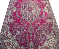 A vintage Persian Tabriz rug featuring a central medallion and intricate floral patterns in magenta.