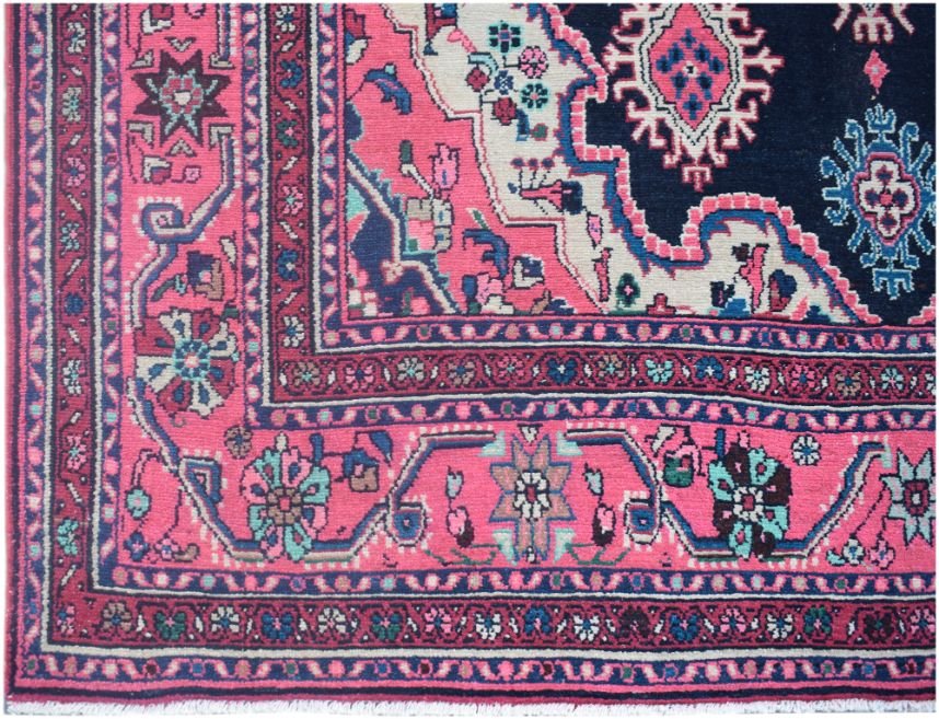A vintage Persian Tabriz rug featuring a vibrant pink border and a dark blue central medallion.