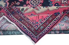 A folded vintage Persian Tabriz rug featuring intricate floral patterns in pink, blue, and cream.
