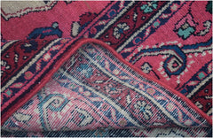 A corner of a vintage Persian Tabriz rug is folded back to reveal its hand-knotted wool construction.
