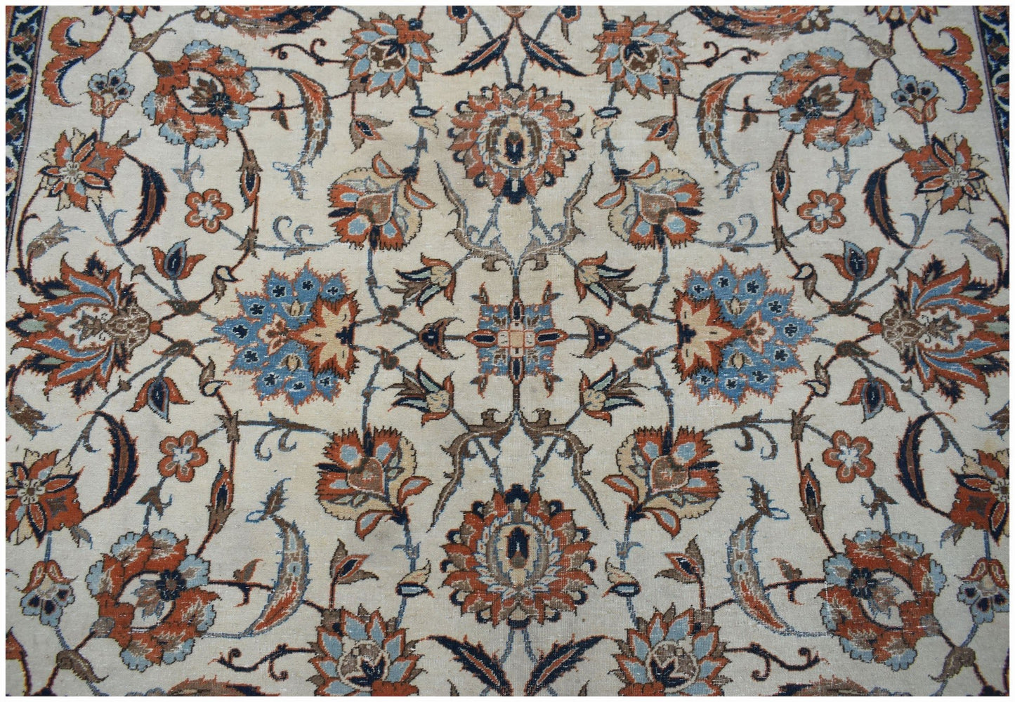 A vintage Persian Kashan rug featuring intricate floral patterns in blue, orange, and cream tones.