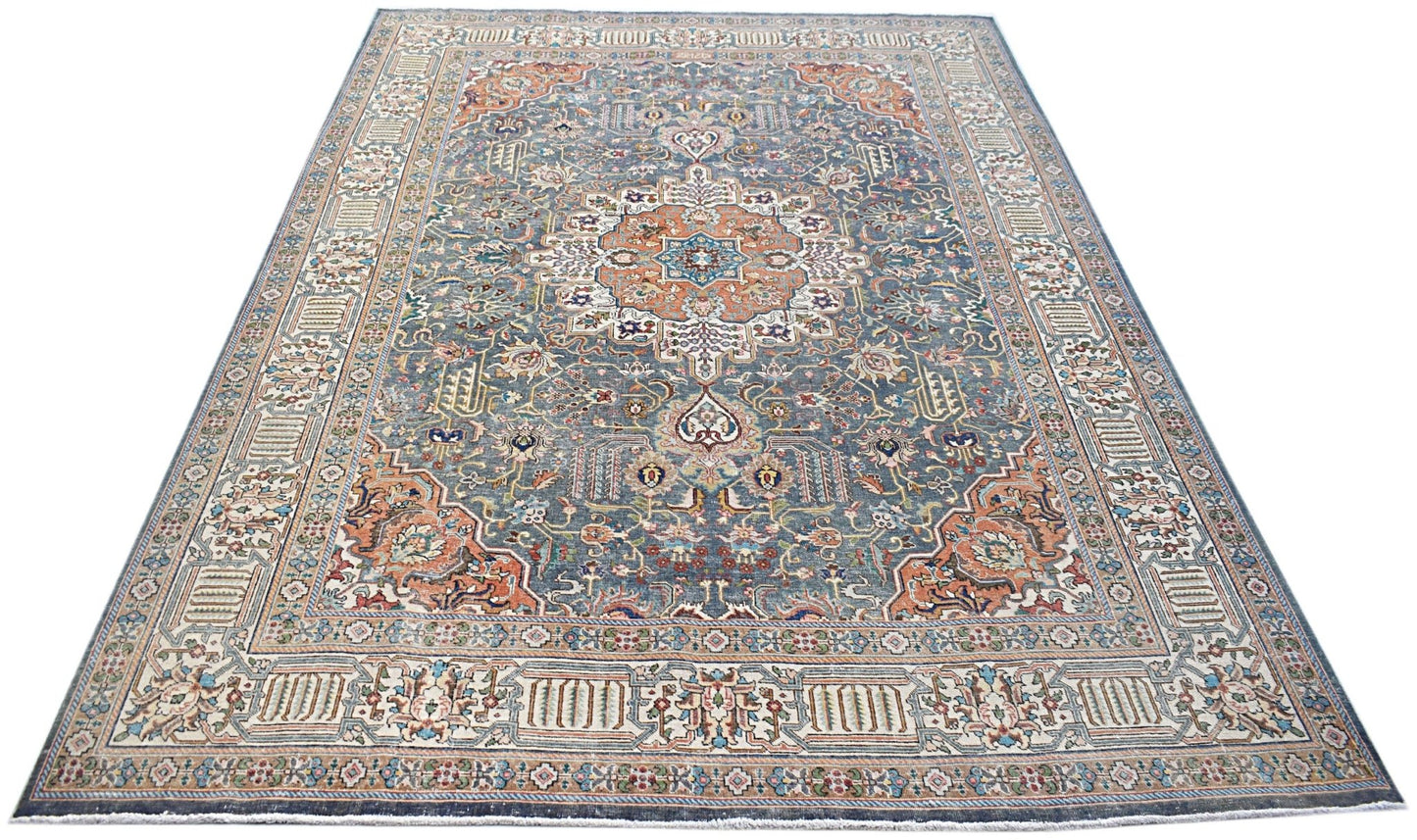 A vintage handwoven Persian Tabriz rug featuring intricate floral patterns in blue and orange tones.