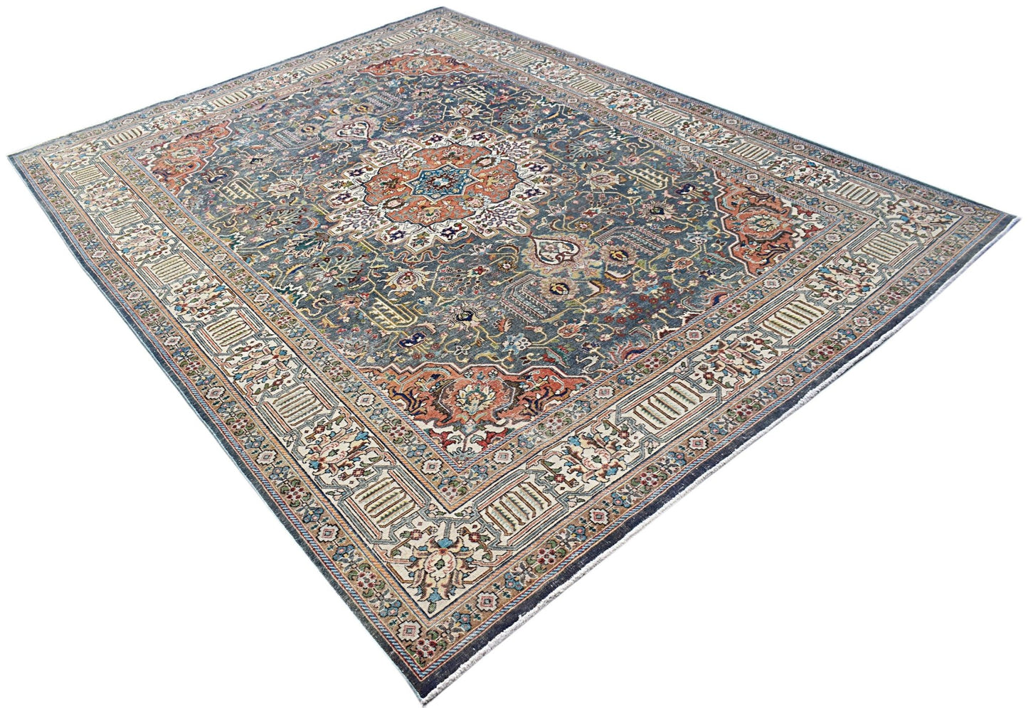 A vintage handwoven Persian Tabriz rug featuring intricate floral patterns in blue and rust tones.