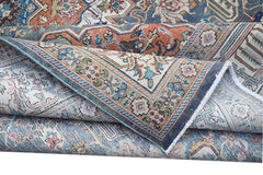 A folded vintage Persian Tabriz rug featuring intricate floral patterns in blue and orange tones.