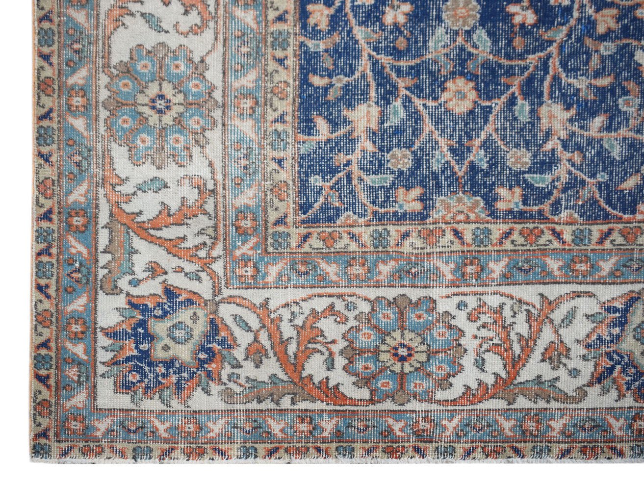 A vintage Persian Tabriz rug featuring a blue central field with floral patterns and cream borders.