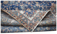 A vintage Persian Tabriz rug featuring a blue and cream floral pattern with a folded corner.