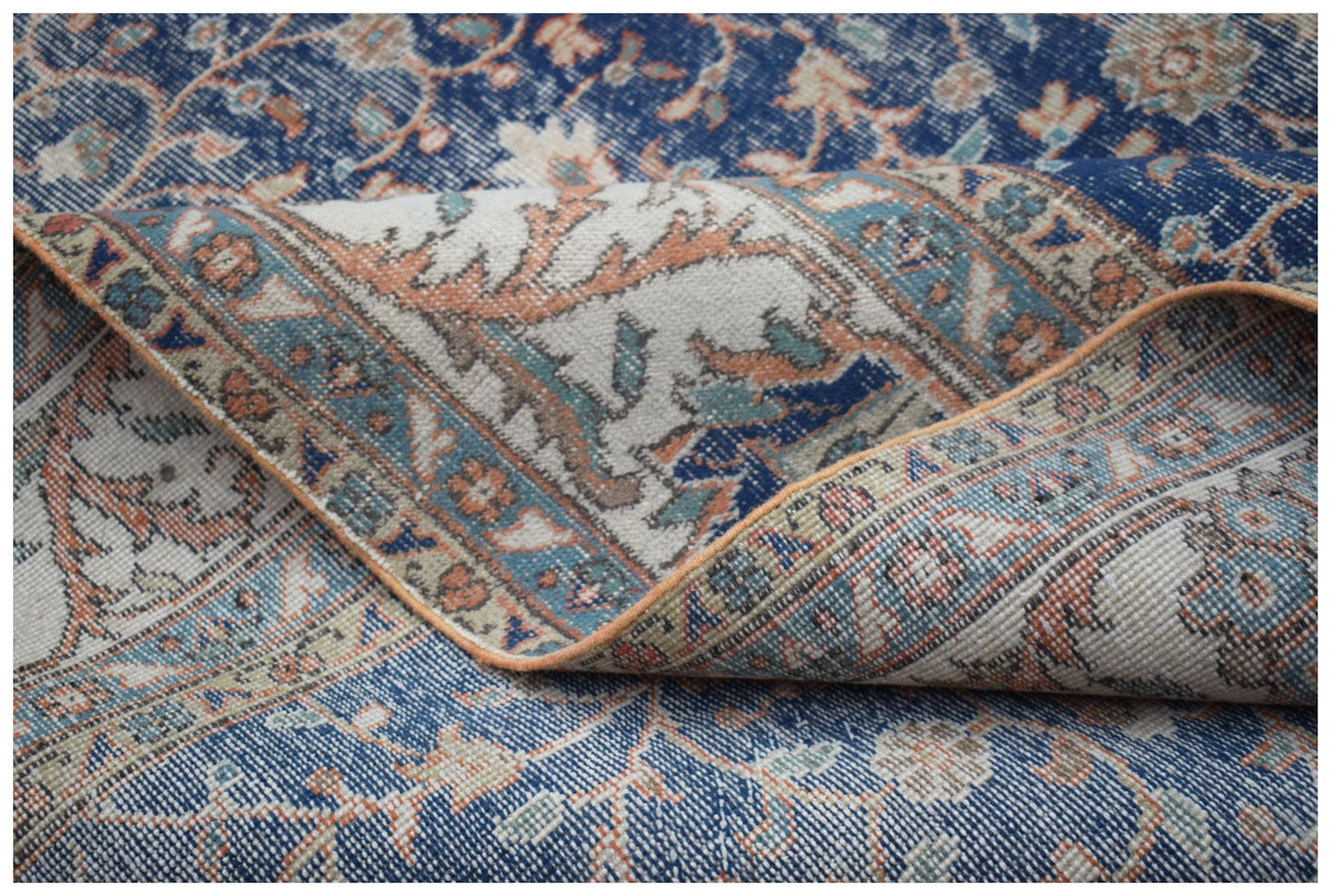 A vintage handwoven Persian Tabriz rug featuring a blue floral pattern with orange and cream accents.