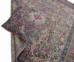 A vintage handwoven Persian Tabriz rug featuring intricate floral patterns in a muted color palette.