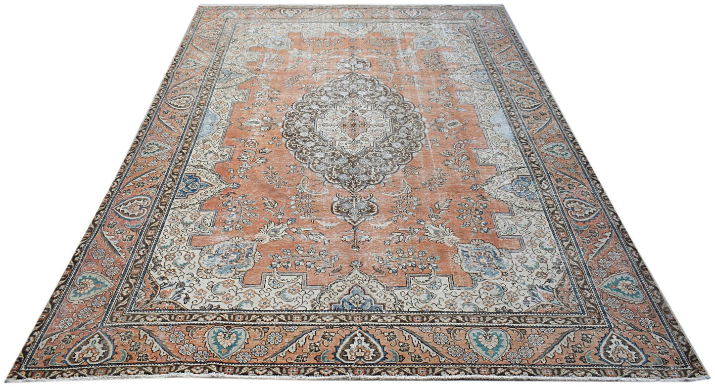 A vintage handwoven Persian Tabriz rug featuring a central floral medallion on an orange field.