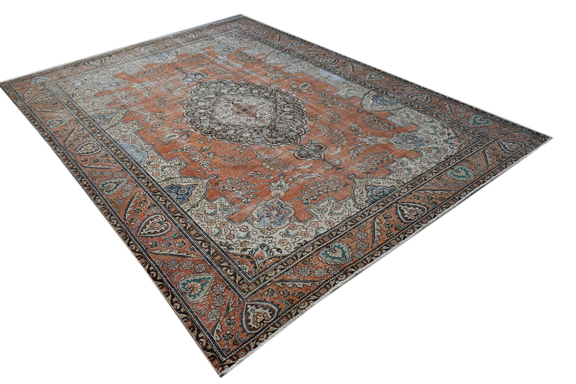A vintage handwoven Persian Tabriz rug featuring a floral medallion pattern in orange and blue.