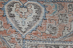 A close-up view of a vintage Persian Tabriz rug featuring intricate floral patterns in muted tones.