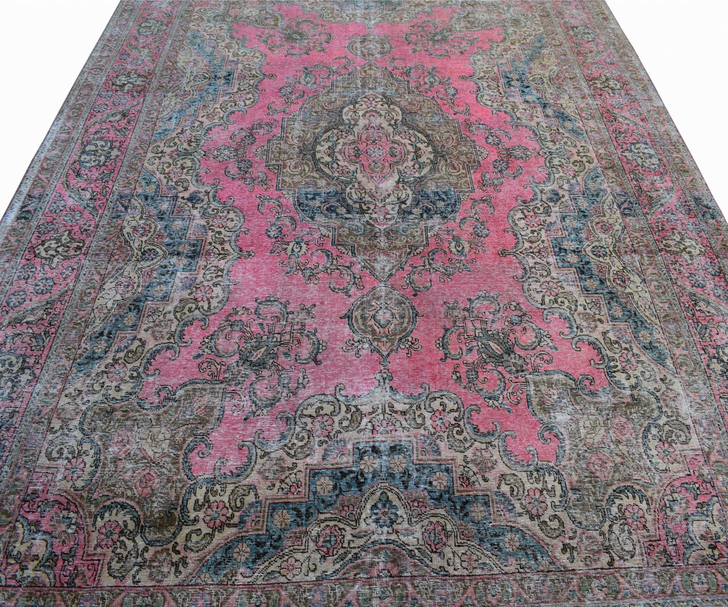 A vintage Persian Tabriz rug featuring a central floral medallion on a pink field with blue accents.