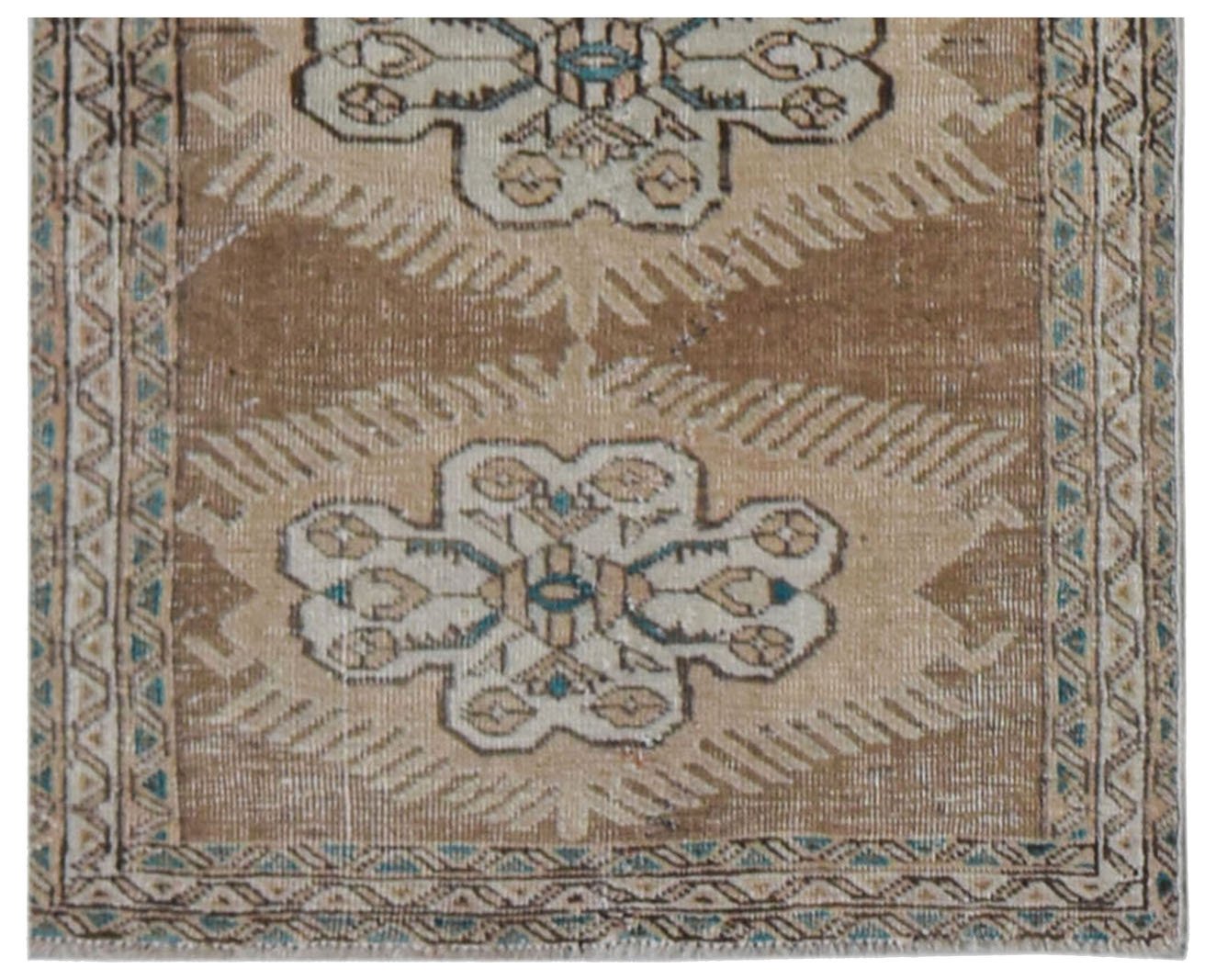 A vintage handwoven Persian runner featuring a repeating floral medallion pattern in tan and blue.