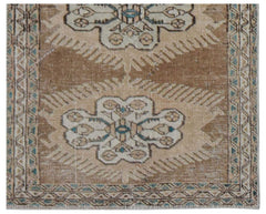 A vintage handwoven Persian runner featuring a repeating floral medallion pattern in tan and blue.