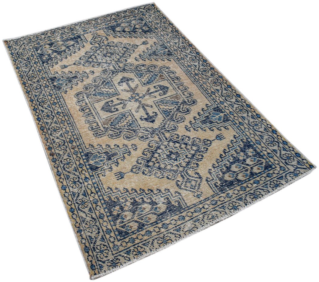 A vintage handwoven Persian rug featuring a blue and beige geometric pattern on a wool pile.