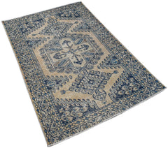 A vintage handwoven Persian rug featuring a blue and beige geometric pattern on a wool pile.