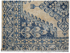 A vintage Persian Wiss rug featuring a blue geometric pattern on a beige wool background.
