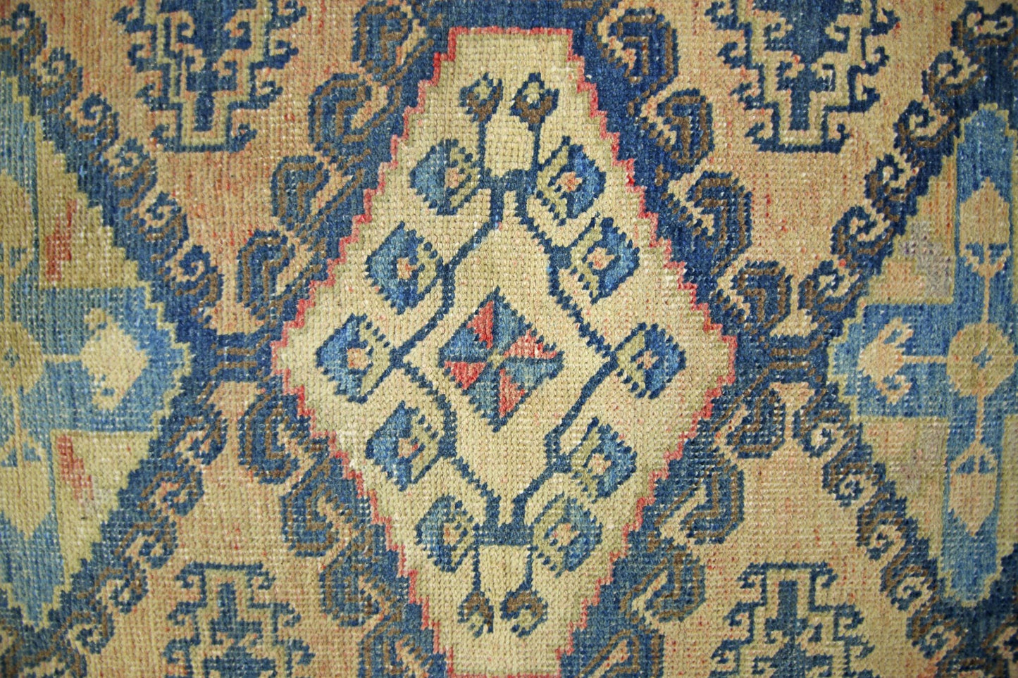 A vintage Persian Wiss rug featuring a geometric diamond pattern in blue, beige, and red tones.