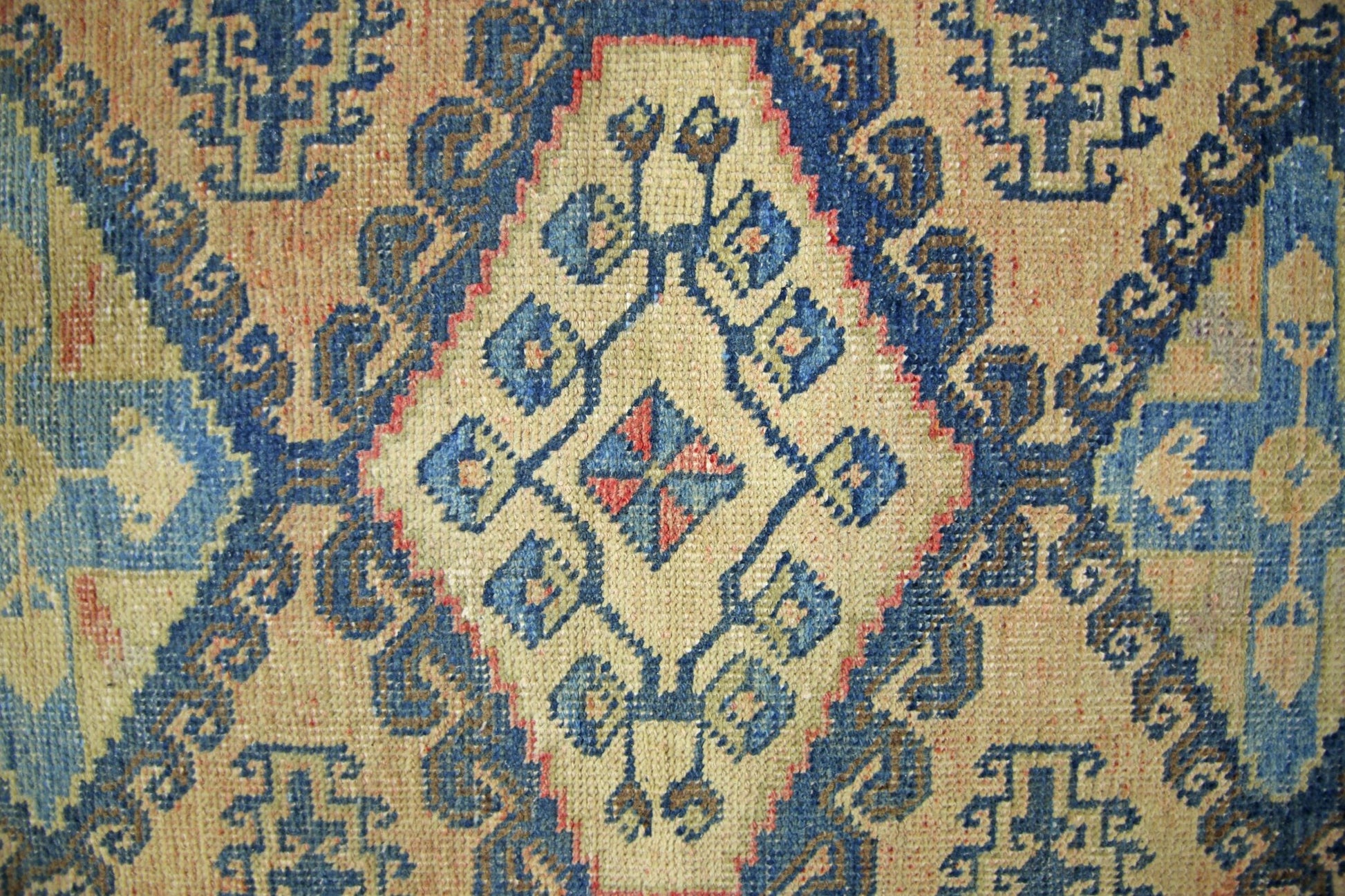 A vintage Persian Wiss rug featuring a geometric diamond pattern in blue, beige, and red tones.