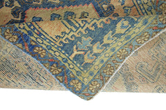 A corner of a vintage Persian Wiss rug is folded over to show its blue and tan patterned design.