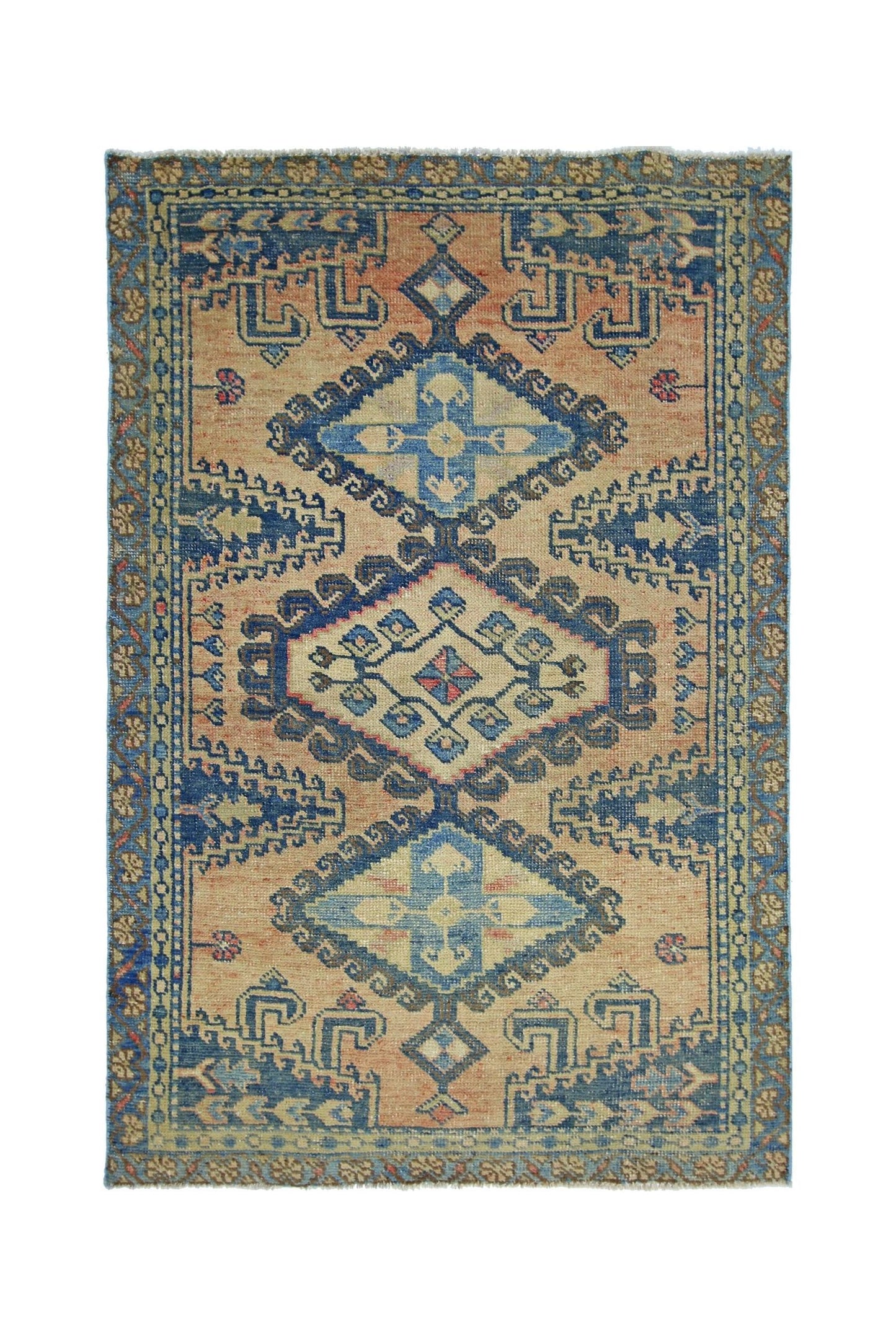 A vintage Persian Wiss rug featuring a geometric blue and cream medallion on a peach field.