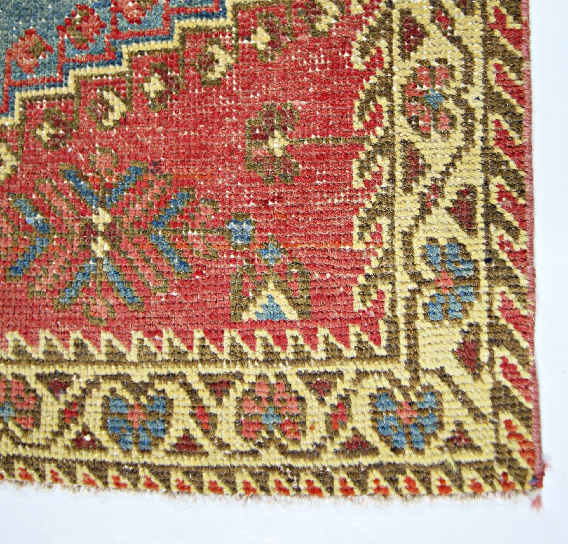 A close-up of a vintage Persian Wiss rug featuring intricate floral patterns in red, blue, and tan.