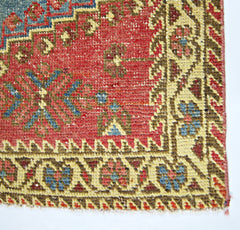 A close-up of a vintage Persian Wiss rug featuring intricate floral patterns in red, blue, and tan.