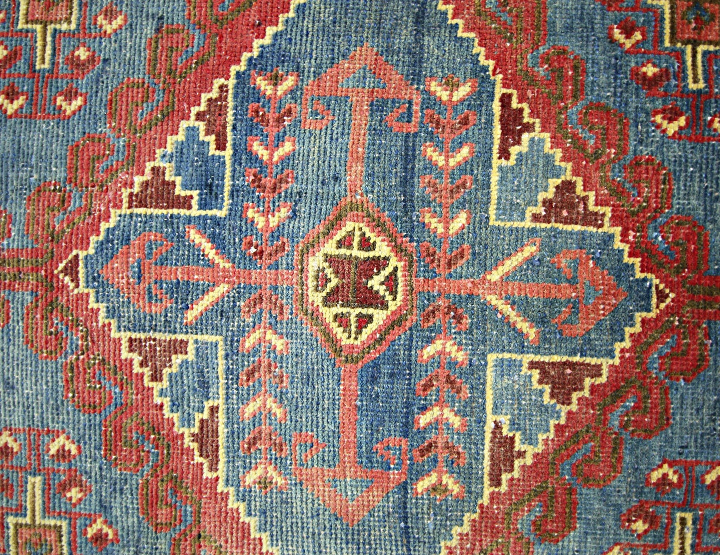 A vintage Persian Wiss rug featuring a geometric blue field with red and yellow tribal motifs.