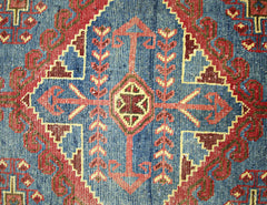A vintage Persian Wiss rug featuring a geometric blue field with red and yellow tribal motifs.