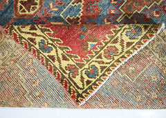 A vintage handmade Persian Wiss rug featuring a folded corner showing its wool and cotton weave.