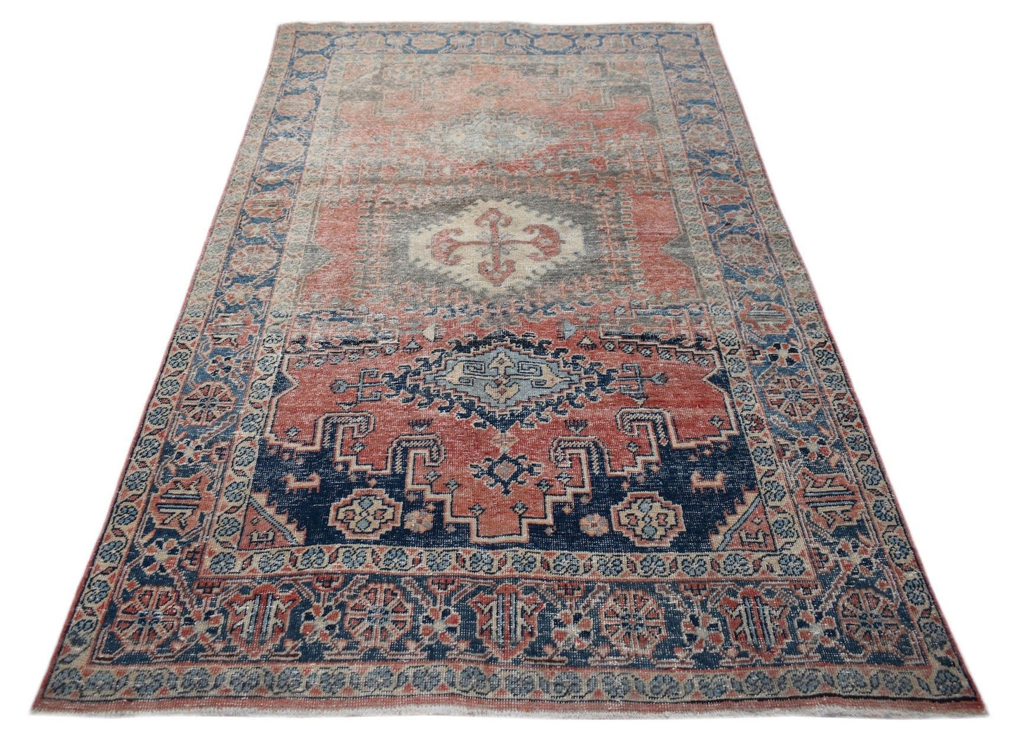 A vintage handwoven Persian wool rug featuring a geometric medallion pattern in red and blue.
