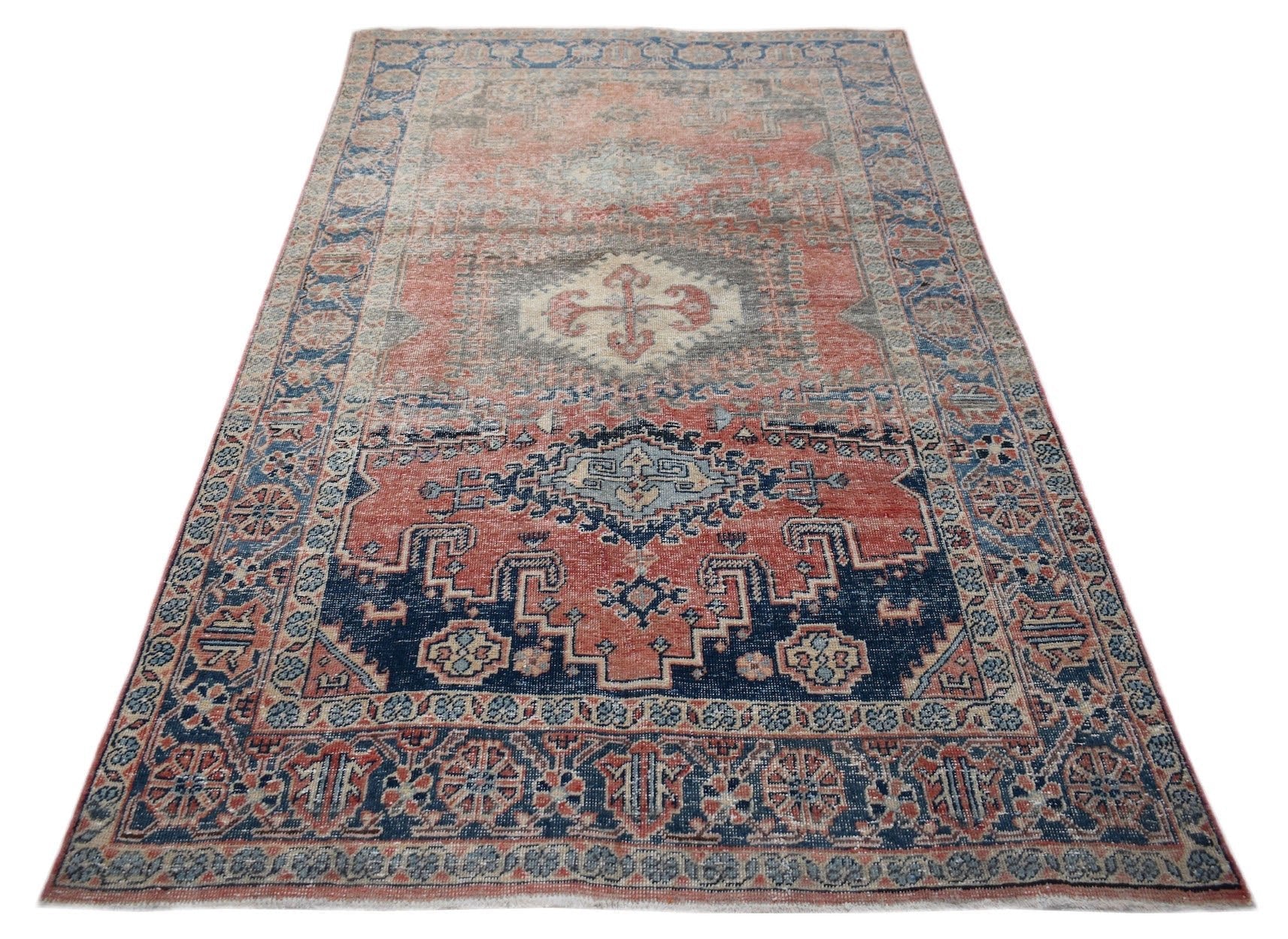 A vintage handwoven Persian wool rug featuring a geometric medallion pattern in red and blue.
