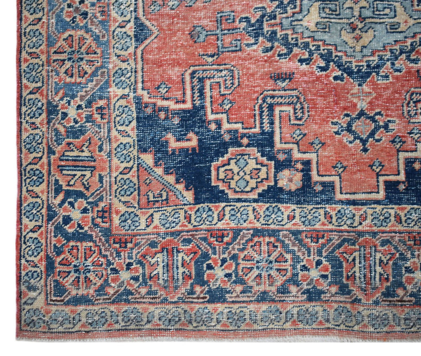 A vintage handwoven Persian rug featuring a geometric pattern in shades of blue and terracotta.