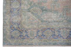 A vintage Persian Wiss rug featuring a faded floral medallion pattern in blue, green, and peach.