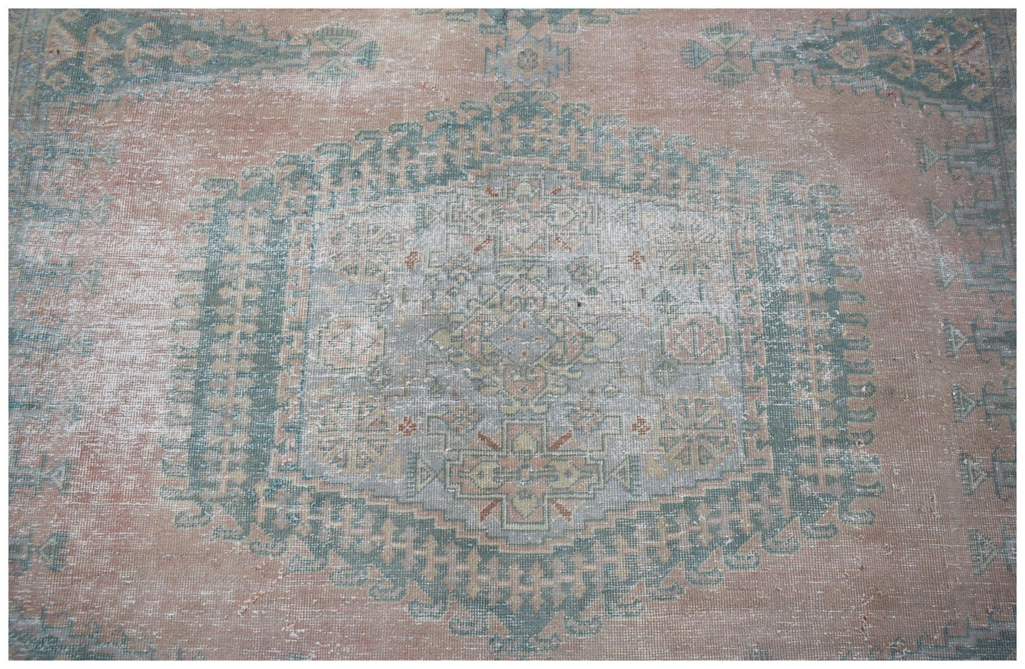A vintage Persian Wiss rug featuring a central medallion in faded pink and sage green tones.