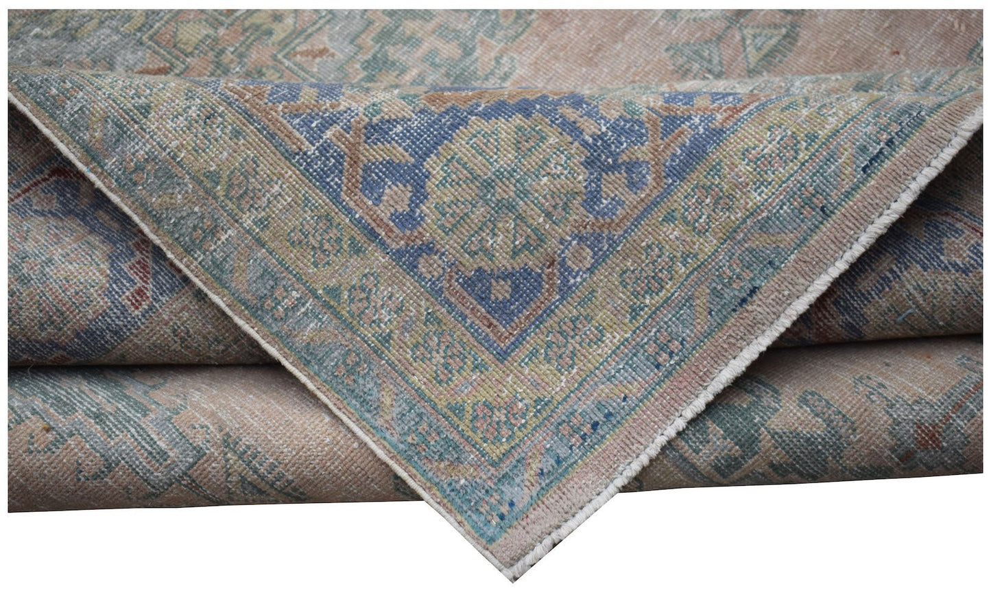 A folded vintage Persian Wiss rug featuring a blue central medallion and intricate floral patterns.