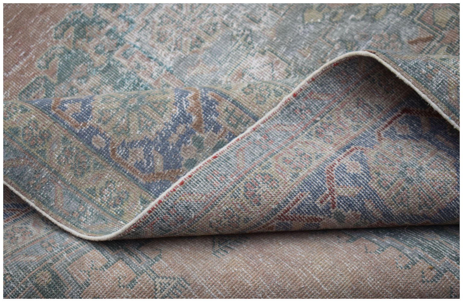 A vintage Persian Wiss rug with a faded floral medallion pattern in muted blue and peach tones.