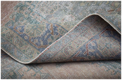 A vintage Persian Wiss rug with a faded floral medallion pattern in muted blue and peach tones.