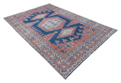 A vintage handwoven Persian rug featuring a central medallion pattern in blue and terracotta tones.