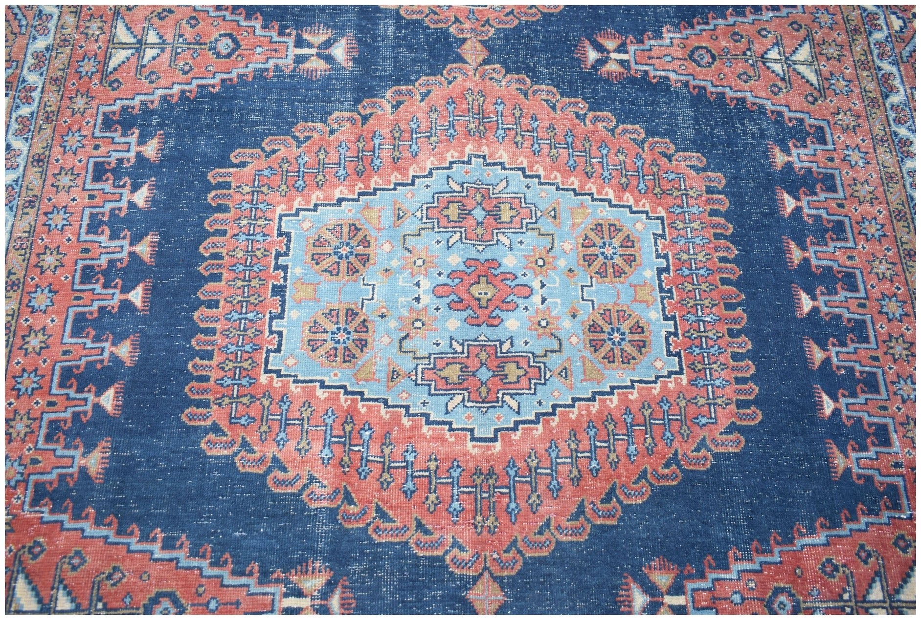 A vintage Persian Wiss rug featuring a central medallion in blue and red geometric patterns.