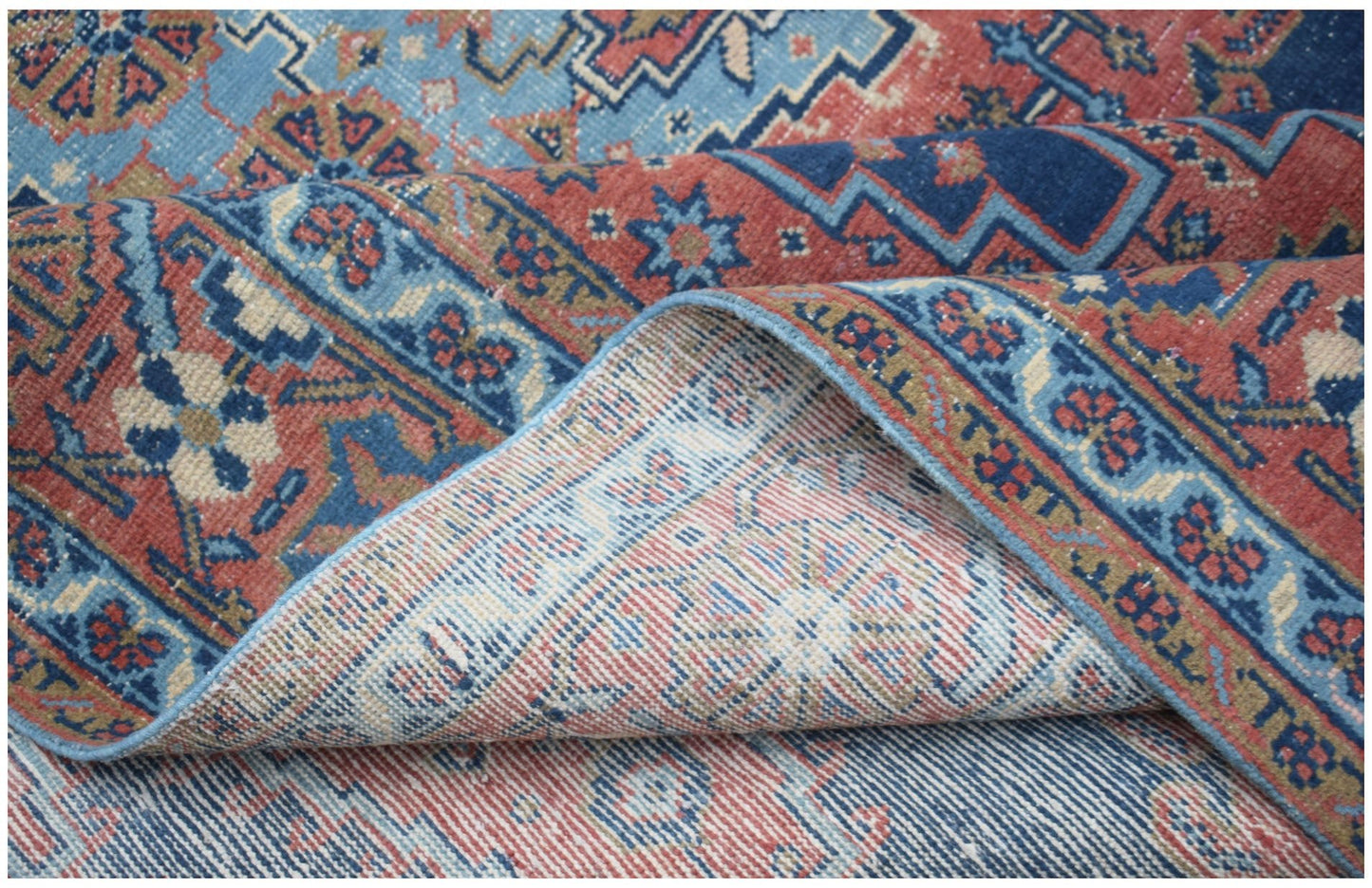 A vintage Persian Wiss rug featuring intricate geometric patterns in shades of blue and red.