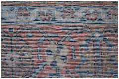 A close-up view of a vintage Persian rug featuring intricate floral patterns in red, blue, and tan.