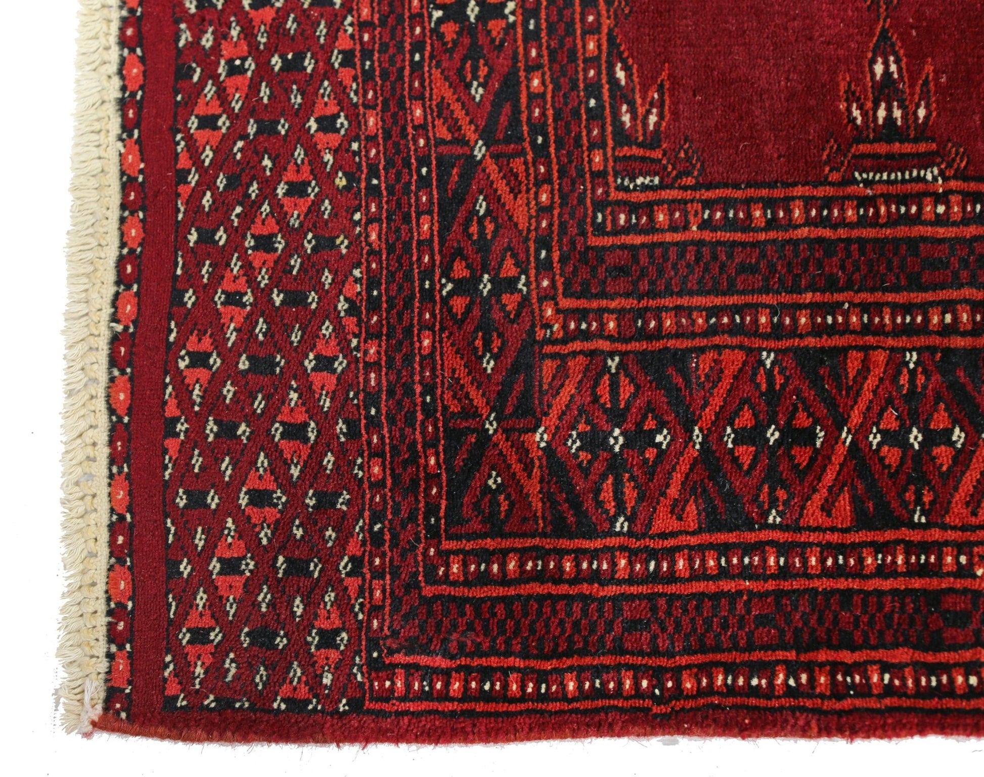 A vintage Pakistani Princess Bokhara rug featuring a geometric red and black pattern with fringe.