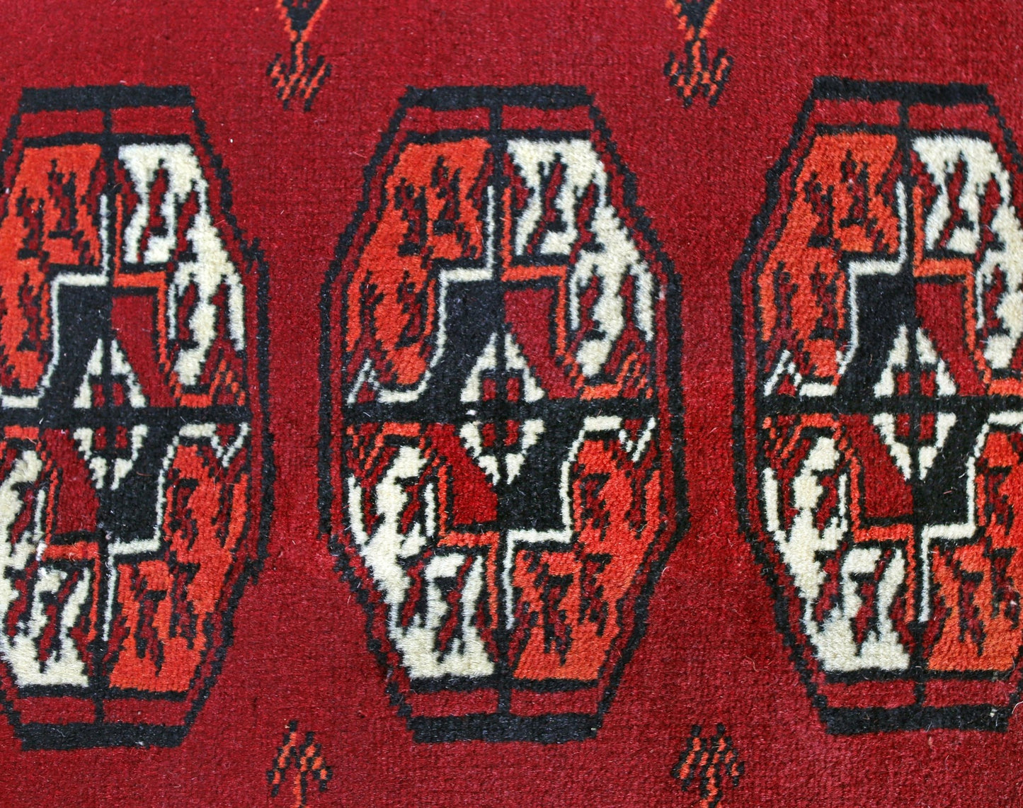 A vintage Pakistani Princess Bokhara rug featuring repeating geometric motifs in red, black, and white.